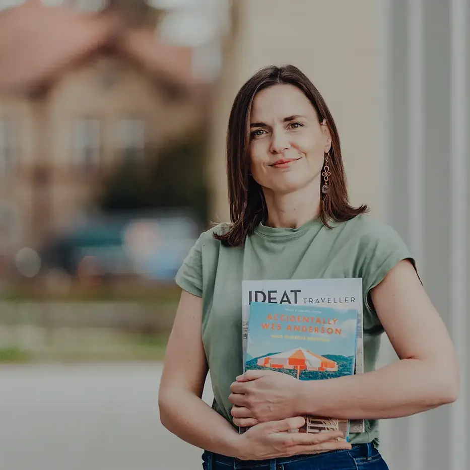 Theresa, Redakteurin bei wir unterwegs, hält ein Reisemagazin in den Händen und lächelt. Sie steht für kreative Inhalte und authentische Einblicke in intensive Gruppenreisen und Teamevents.