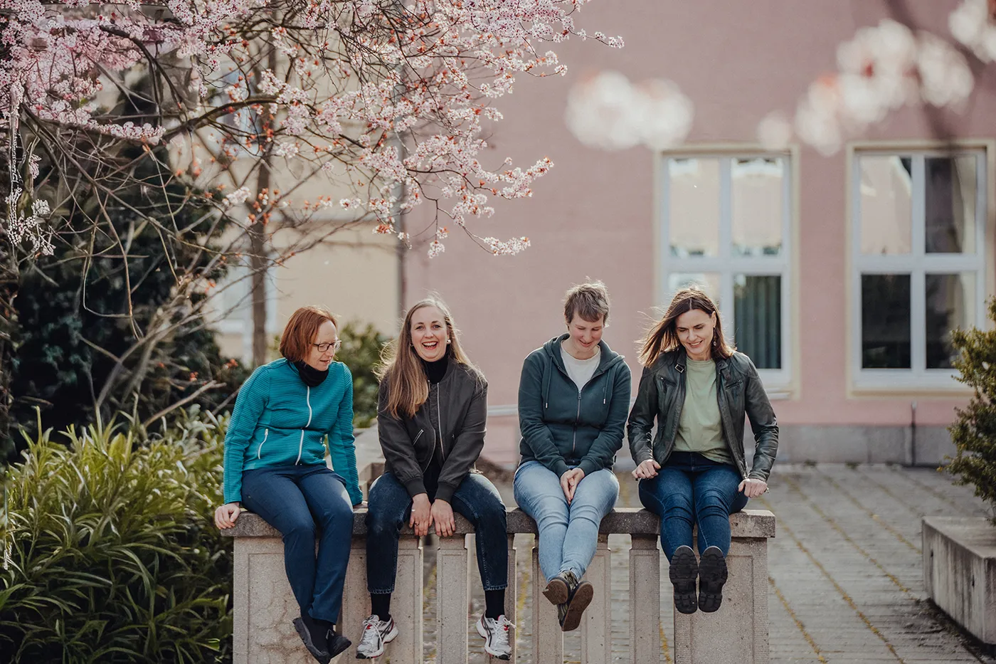 Das Team von wir unterwegs sitzt lachend unter blühenden Kirschbäumen. Die Expertinnen für intensive Gruppenreisen und persönliche Teamevents genießen gemeinsam den Moment.