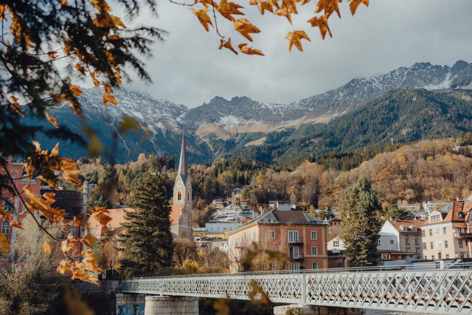 Eine Brücke aus Eisenfachwerk mit sich kreuzenden Streben führt über den Inn hinüber in die Altstadt von Innsbruck.